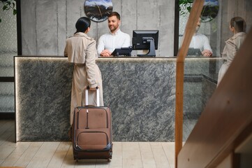 Elegant Business Woman with Travel Trolley Luggage in Hotel Lobby