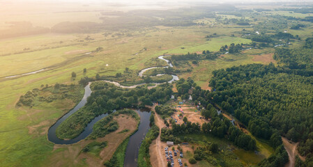 Panorama view from above of the summer landscape. Orange sunset sky, fields and forests, rivers and roads