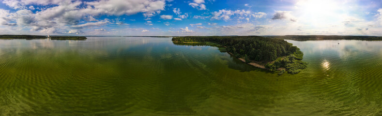 Panaramic view from a height of a flying drone on a summer landscape. Lake and river, field and forest.