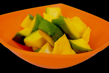 Side View Of Slices of Mango for Mango Pickle in Saffron Color Bowl, Isolated In Black Background
