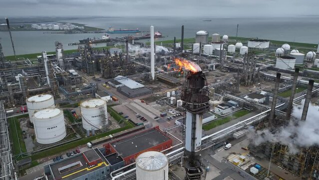 Aerial view of a chemical plant at sunset. Drone shot. Curling fire and cumin smoke filling the sky. Smoking chimneys from the factory. Chimneys of an oil refinery at sunrise pollute the environment