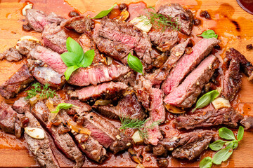 Sliced juicy medium rib eye steak on wooden board. Top view.