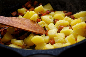 Potatoes and bacon on frying pan
