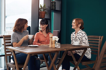 Coffee, women and together in coffee shop for connection, communication and friends in city. Happy, conversation and reunion in restaurant for gossip, discussion and chat with people on weekend