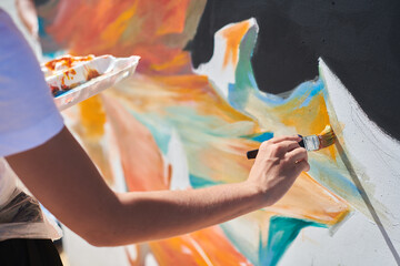 Female painter hand passionately paints picture with paintbrush for outdoor street exhibition using...