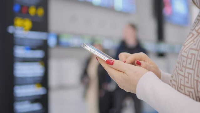 Woman in airport terminal using smartphone to check flight information, text, and updates on screen