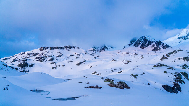 Mountain slope with snow and rocks chot during the blue hour in French alps
