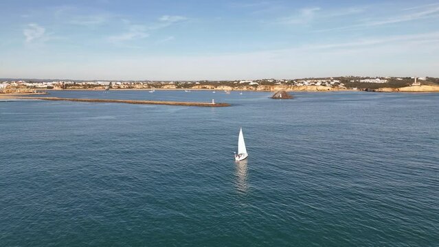 The yacht is sailing towards the entrance to the harbor of Portimao, Portugal