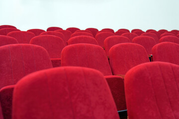 Rows of empty red velvet chairs in a hall, awaiting an audience