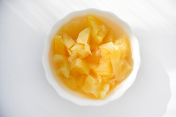 Canned pineapples in a white cup. Chopped pineapples.
