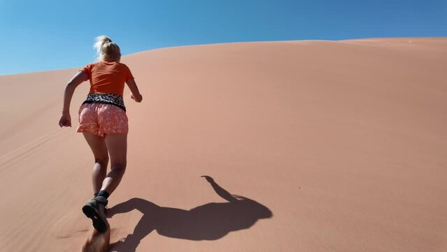 Woman conquering Empty Quarter dunes in Oman, a solitary ascent against golden sands. Girl climbing the Rub' al-Khali desert dunes.