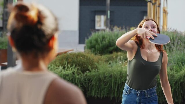 Happy girl friends playing ping pong table tennis, having fun together at the University campus 