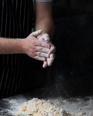 Close up of male baker hands kneading the dough with flour powder.