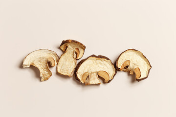 Dry slices of porcini as creative pattern, dehydrated food boletus mushrooms, top view, flat lay, beige background, minimal style. Natural food ingredient wild forest white mushroom, healthy eating