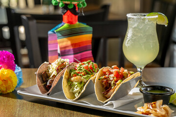 A Trio of Tasty Tacos - Suadero (braised brisket on blue corn tortilla), Grouper and Shrimp tacos with house-made salsa verde, grilled onion and lime, with a margarita.