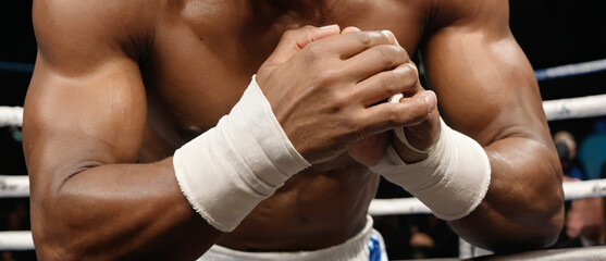 A close-up of a boxer's muscular arms wrapped in white tape, creating an intense and focused atmosphere. Ideal for sports event promotions, fitness campaigns, or boxing match advertisements. - Powered by Adobe