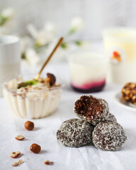 Chocolate candies with coconut flakes against dairy desserts