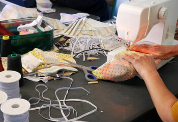 les mains d'une couturière tenant un tissu sous la lumière de sa machine à coudre