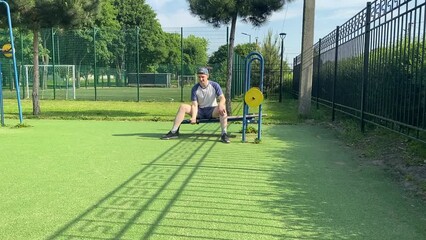 A young man in sportswear engages in a workout, using a sport tool for physical exercises at the outdoor gym in the morning. His dedication to fitness performs training routine with focus and energy