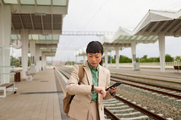 Asian businesswoman checking the time on her wristwatch at the train station