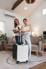 Two Young Women Preparing for Travel with Suitcases Indoors, Concept of Friendship and Summer Travel
