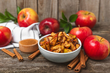 Apples with cinnamon on a textured wooden background. Fragrant red spiced apples with cinnamon sticks and star anise. Apple slices with spicy spices. Place for text. Copy space. Harvesting. Fruits.
