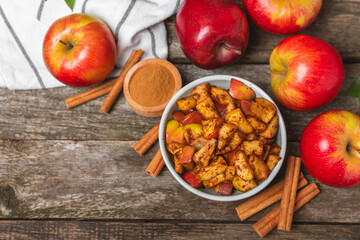 Apples with cinnamon on a textured wooden background. Fragrant red spiced apples with cinnamon sticks and star anise. Apple slices with spicy spices. Place for text. Copy space. Harvesting. Fruits.