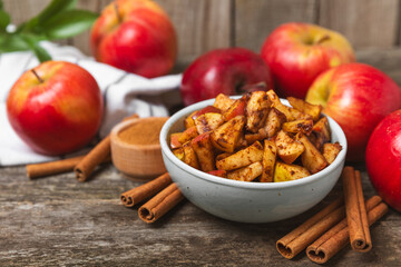 Apples with cinnamon on a textured wooden background. Fragrant red spiced apples with cinnamon sticks and star anise. Apple slices with spicy spices. Place for text. Copy space. Harvesting. Fruits.