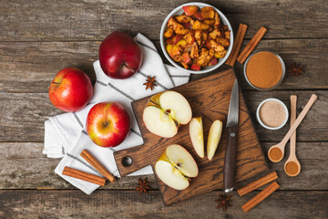 Apples with cinnamon on a textured wooden background. Fragrant red spiced apples with cinnamon sticks and star anise. Apple slices with spicy spices. Place for text. Copy space. Harvesting. Fruits.