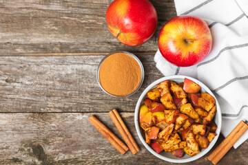 Apples with cinnamon on a textured wooden background. Fragrant red spiced apples with cinnamon sticks and star anise. Apple slices with spicy spices. Place for text. Copy space. Harvesting. Fruits.