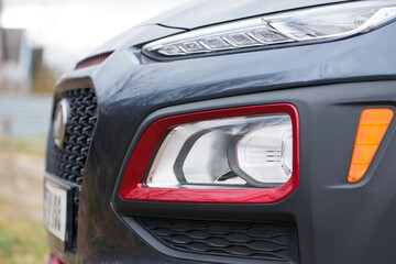 headlight of modern prestigious car closeup. beautiful headlights of a car. dark gray color, red...