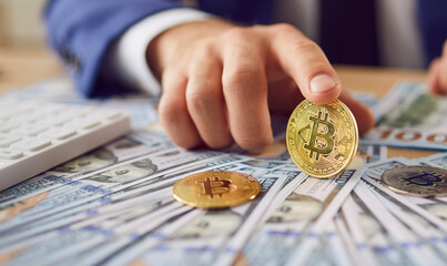 Close up of metal shiny bitcoin crypto currency coin on US dollar bills in hand of successful...