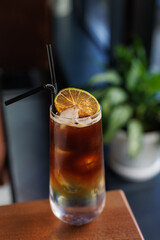 cold refreshing ice coffee in a transparent glass on a wooden table
