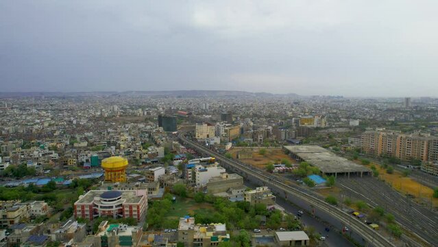 aerial descending drone shot showing densely populated buildings houses offices cityscape of jaipur with monsoon clouds overhead showing this serene peaceful city