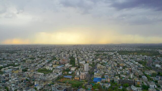 side panning aerial drone shot showing densely populated buildings houses offices cityscape of jaipur with monsoon clouds overhead showing this serene peaceful city