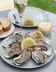 Champagne sparkling wine in glasses and oysters from Arcachon bay served on oysters farm in Gujan-Mestras, with lemon, baquette bread, butter