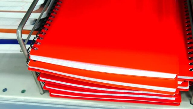 Close-up of spring checkered notebooks with red covers and a male hand takes one from the top