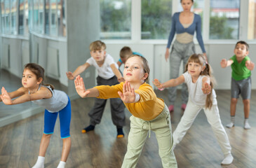 Girl participates in childrens group lesson, learning to dance twerk. Devotion of modern trend pastime, active lifestyle and hobbies