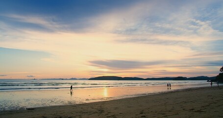 A serene sunset at a beach, with silhouettes of people enjoying the tranquil scenery