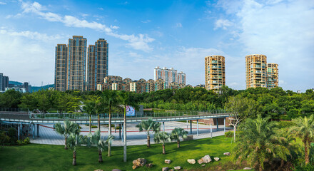 a panoramic view of urban cityscape with residential buildings as background, photo inside an urban park of downtown shenzhen, china