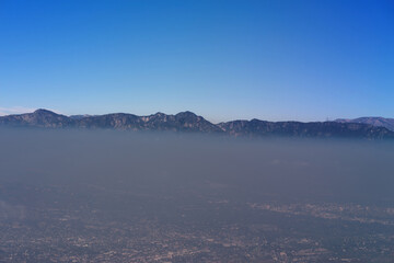 Aerial view, looking north, showing a heavy layer of smog over the Glendale, Eagle Rock, and Pasadena areas with the top of the San Gabriel Mountains in the distance, on May 18, 2024. Mount Wilson is 