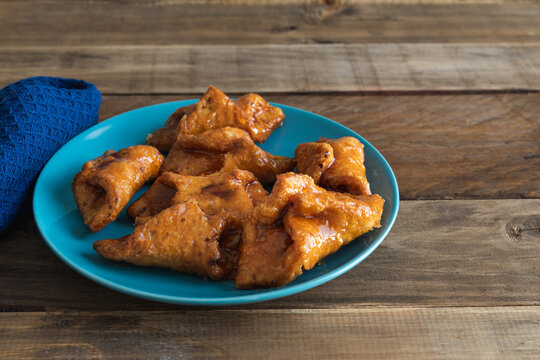 Pesti?os. Typical sweet of Christmas and Easter. Carnival fried sweets in blue plate on wooden background. Copy space.