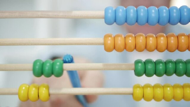 Blurred Shooting with a Man Using a Balls Calculator. A Counter with Colored Balls, a Tool Used by Kids for Learning to Calculate.