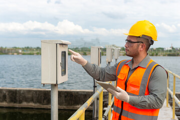an engineer point his finger at the valve gauge plumbing system and type it down on a tablet to check the gauge at standard value, waste water treatment, tablet controller system