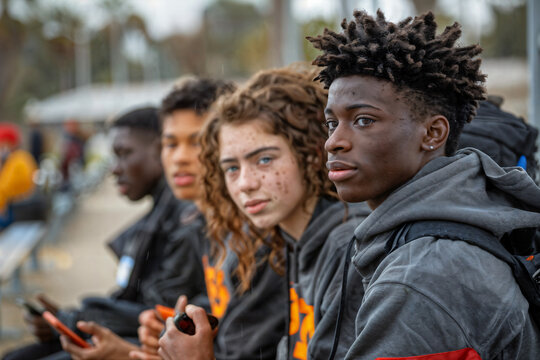 High School Sports Team in Uniform Sitting and Using Phones