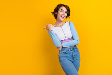 Photo of impressed funky lady dressed shirt looking pointing thumb empty space isolated yellow color background