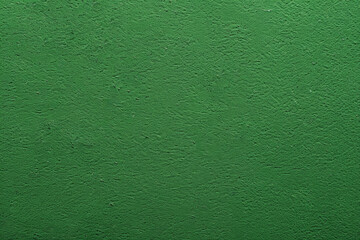 Fototapeta premium Textured background showing a rough concrete wall painted green, providing a bold and vibrant backdrop. This grunge-style image is perfect for adding a touch of urban edge to any project