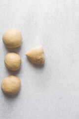 Overhead view of egg noodles dough a marble countertop, homemade egg noodles and egg pasta dough balls, process of making fresh egg noodles