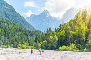 A group of people with dog explore a dry river bed in the scenic surroundings of Triglav National...