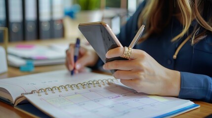 Woman's Hands Using Smartphone And Writing In Planner